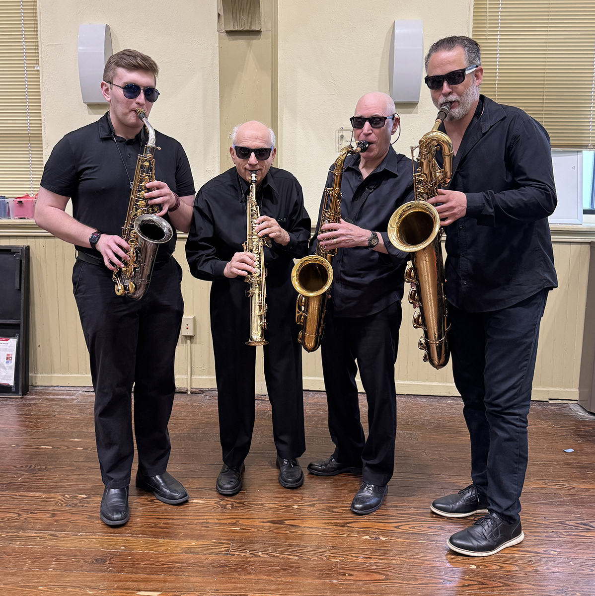 Saxophone quartet poses with instruments and dark glasses